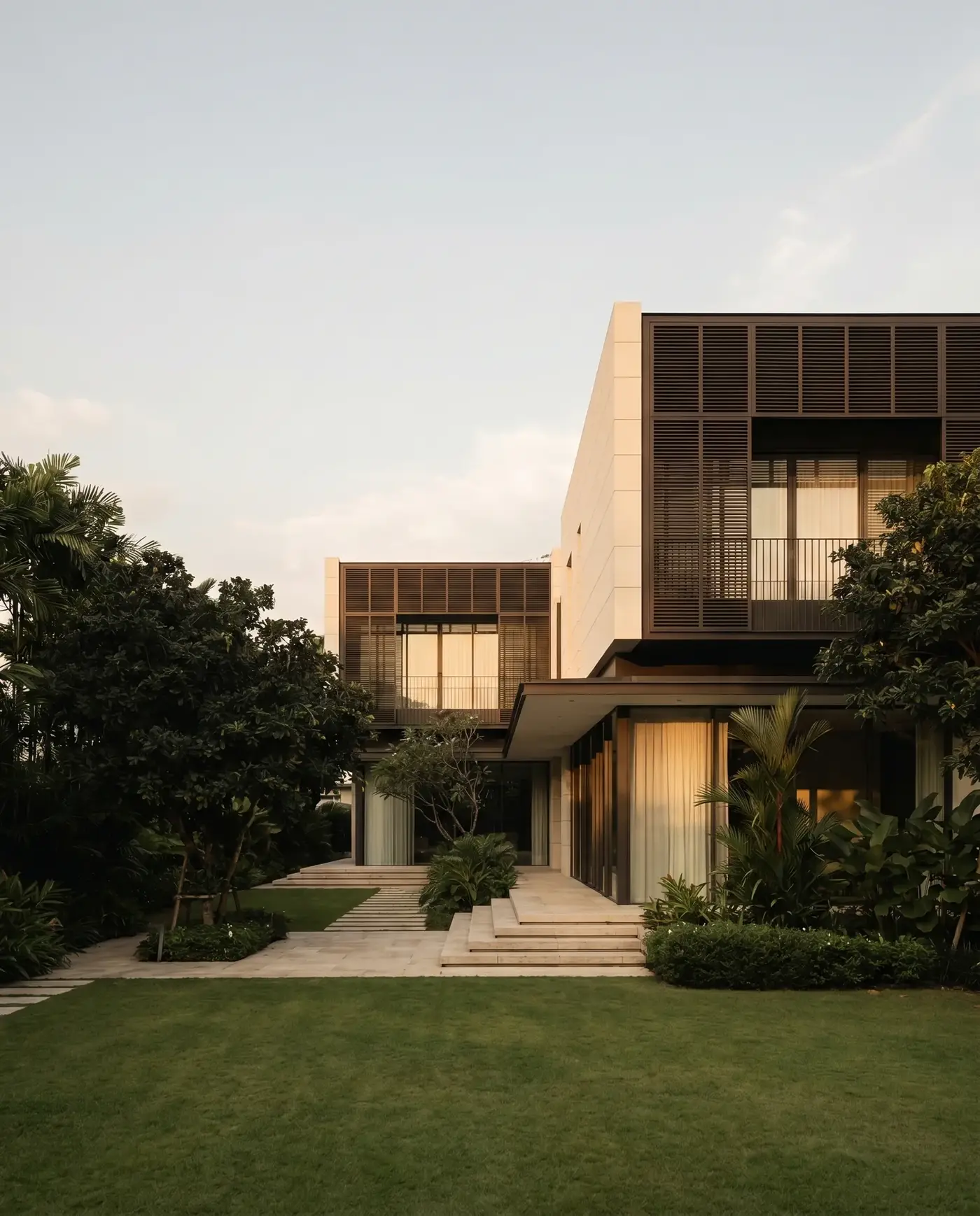 A modern detached residence in the prime districts at dusk, timber screens glowing behind mature trees.